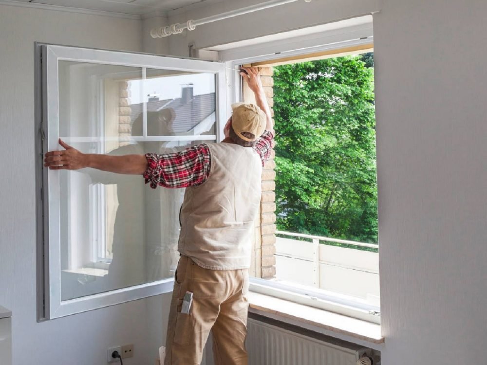 Man installing white-framed window